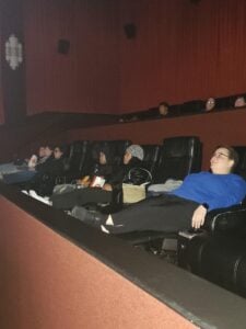 Adults watching a movie in a dark theater.